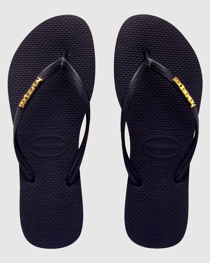 Image of Sandals. Productname: Havaianas - Womens Slim Metal Logo Thongs - Preto/Ouro - in Preto/Ouro colour by brand - Havaianas