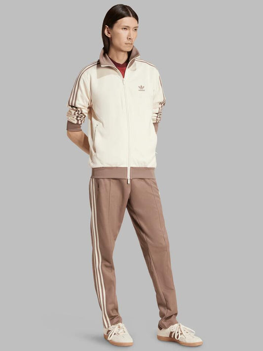 Image of a model wearing Tops. Productname: Adidas Mens Classic Track Top in Wonder White/Trace Brown colour by brand - Adidas