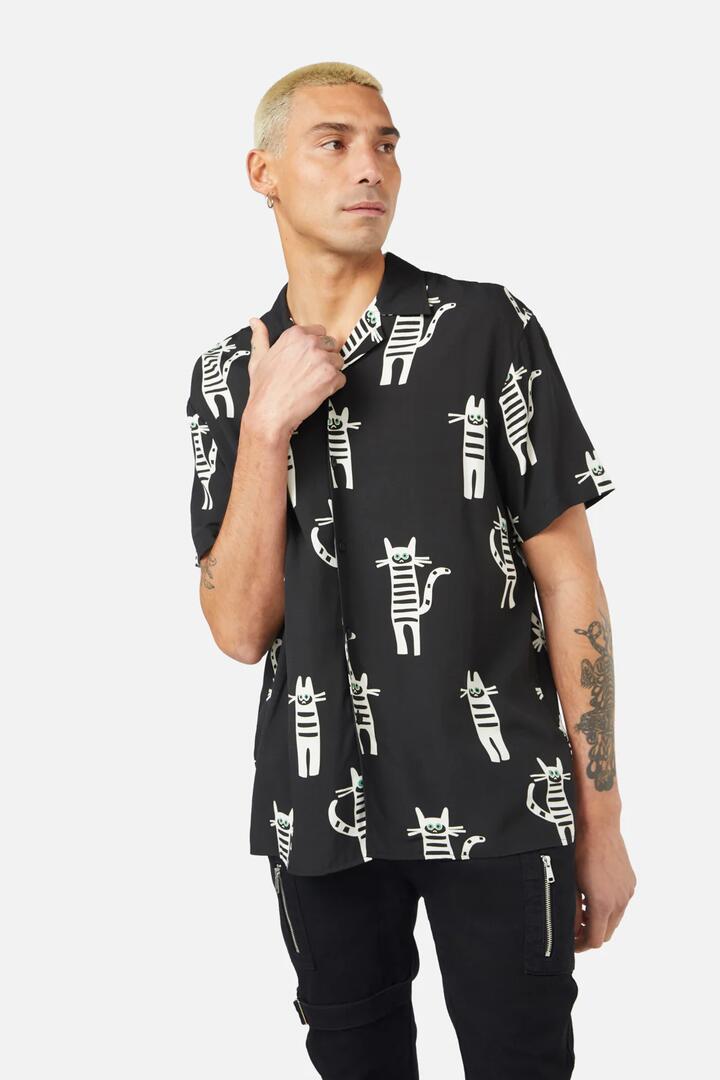 Image of a model wearing Tops. Productname: Peculiar Puss SS Shirt in Black colour by brand - Dangerfield