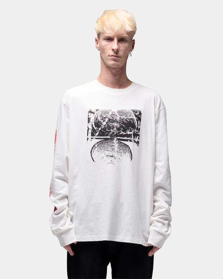 Image of a model wearing Tops. Product name - Former Mens Ode Long Sleeve T-Shirt Oyster in Oyster colour by brand - Former