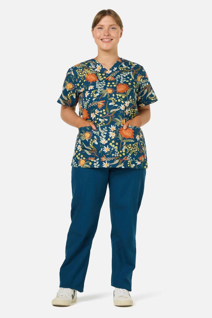 Image of a model wearing Uniforms & Workwear. Productname: Opal Native Top & Pant Scrub Set in Teal colour by brand - Scrubs With Love