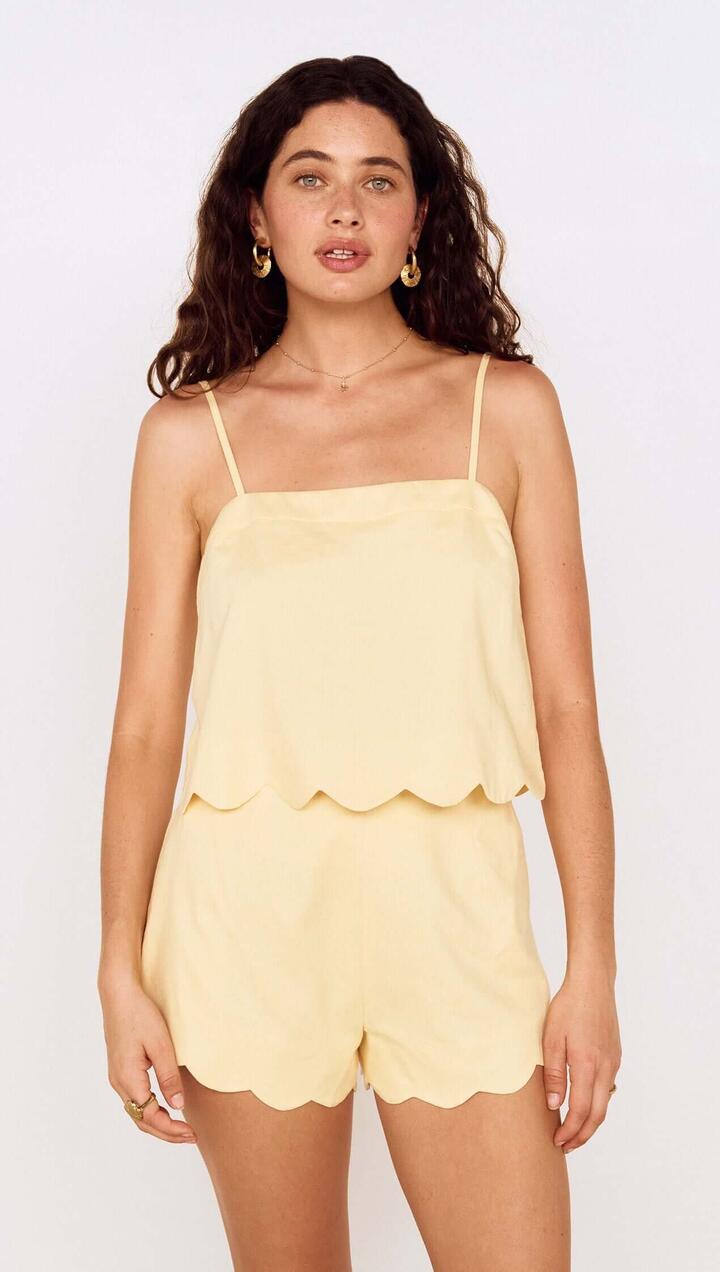 Image of a model wearing Tops. Product name - Butter Yellow Cotton Blend Scallop Hem Cami in Butter colour by brand - MINKPINK