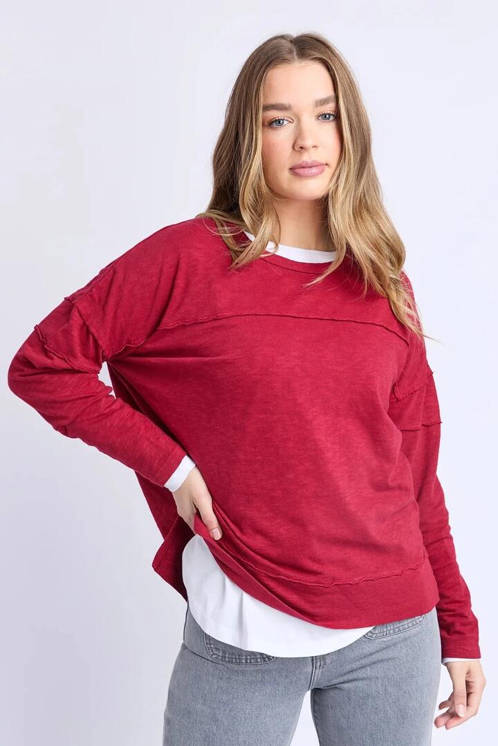 Image of a model wearing Tops. Product name - Jayne Rhubarb Red Front Seam Throw On LS Top in Red colour by brand - Foxwood