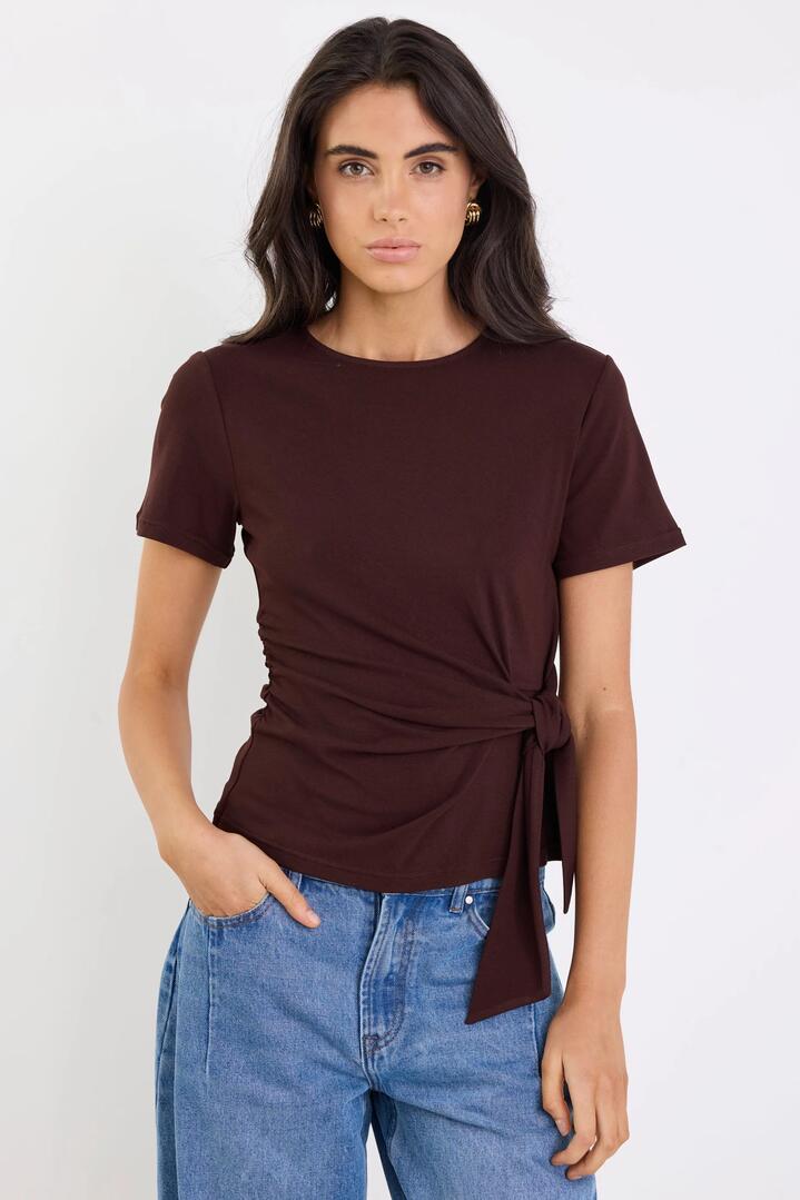 Image of a model wearing Tops. Product name - Loop Chocolate Knot Front Short Sleeve Tee in Chocolate colour by brand - Among the Brave