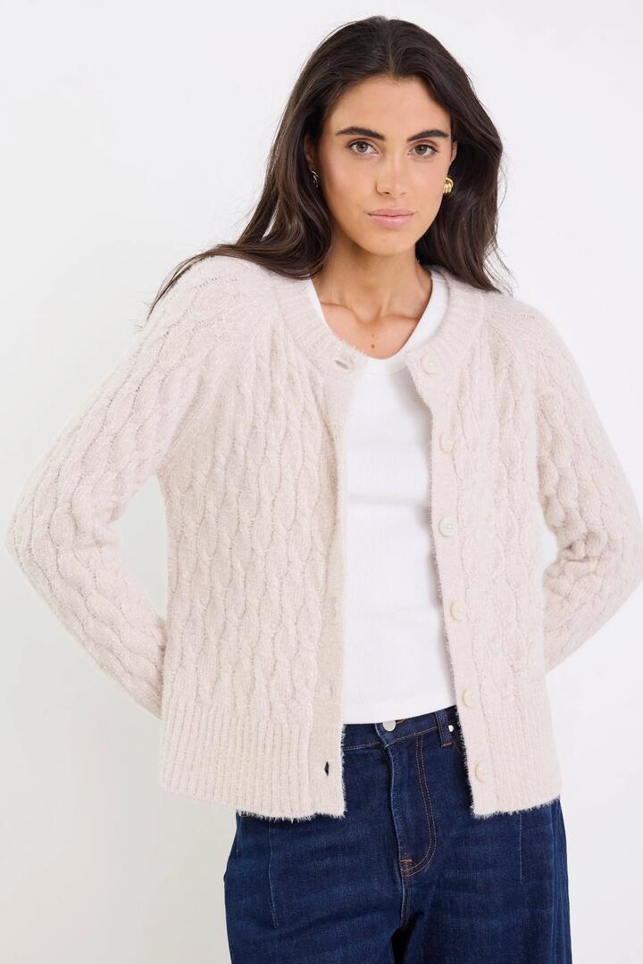 Image of a model wearing Outerwear. Product name - Milestone Oat Crewneck Cable Knit Cardigan in Oat colour by brand - Ivy + Jack