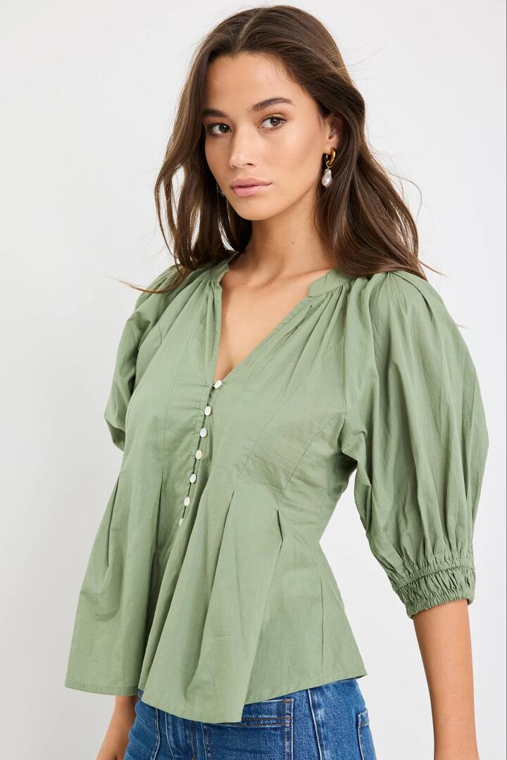 Image of a model wearing Tops. Product name - Esteem Moss Pleated SS Button Through Top in Moss colour by brand - Among the Brave