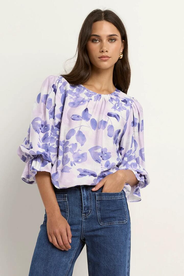 Image of a model wearing Tops. Product name - Candid Ivory Blue Floral Frill Sleeve Crew Neck SS Top in Ivory Blue Floral colour by brand - Ivy + Jack