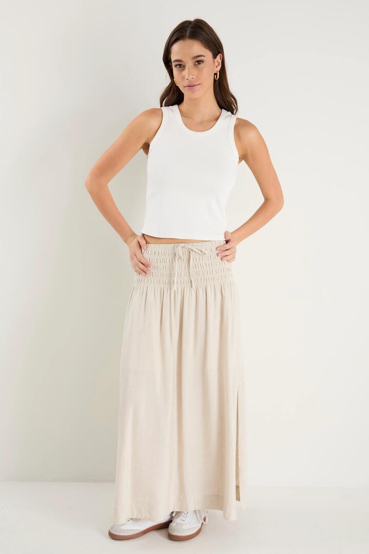 Image of a model wearing Skirts. Product name - Byron Natural Linen Shirred Waist Maxi Skirt in Natural colour by brand - RE:UNION Label
