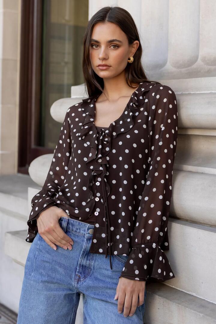 Image of a model wearing Tops. Product name - Bohemian Chocolate Polka Dot Sheer Frill Front Blouse in Chocolate Polka Dot colour by brand - Among the Brave