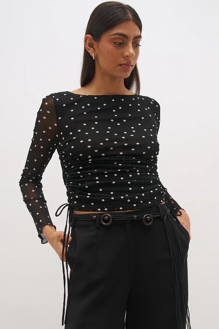 Image of a model wearing Tops. Product name - Vesper Black Polka Dot Side Gather Mesh LS Top in Black colour by brand - Mon Renn