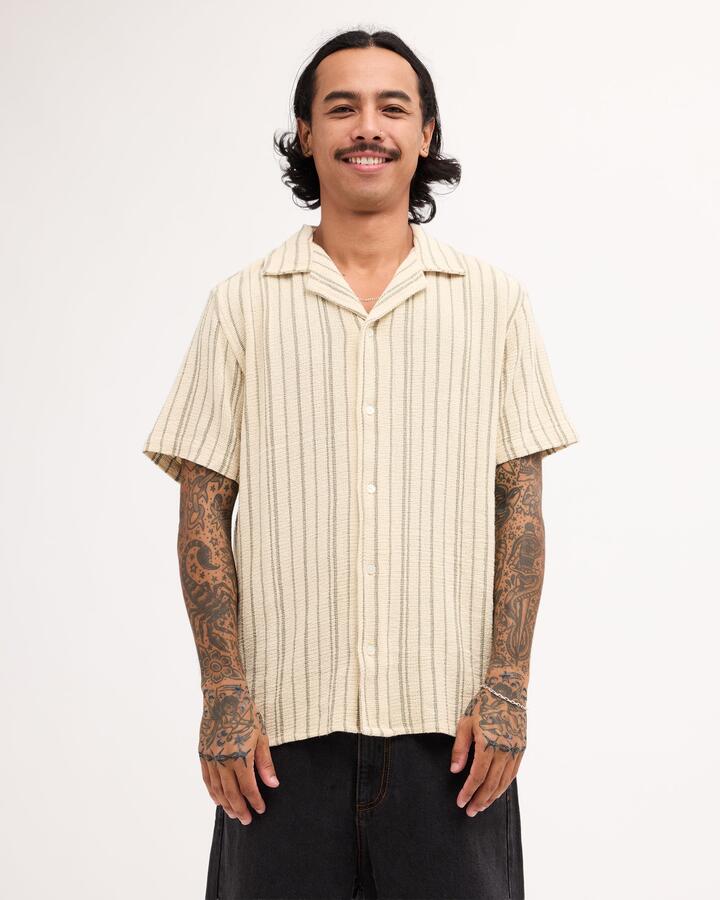 Image of a model wearing Tops. Product name - RVCA Mens Vacancy Stripe Short Sleeve Shirt Latte in Latte colour by brand - RVCA