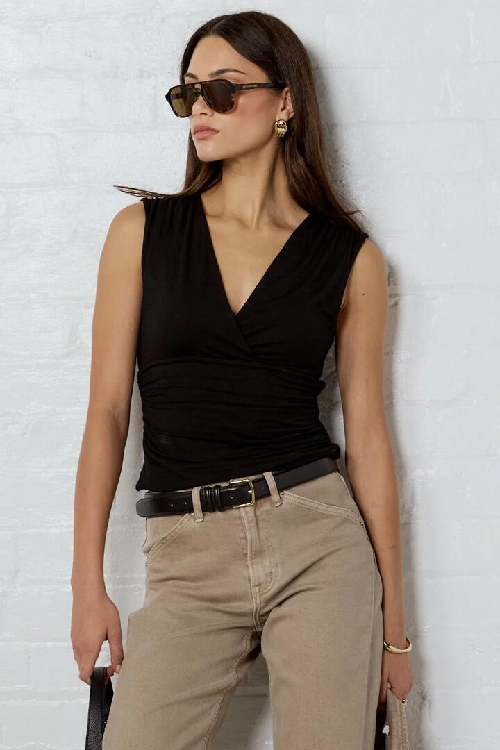 Image of a model wearing Tops. Product name - Connect Black Jersey Cross Front Sleeveless Top in Black colour by brand - Stories be Told