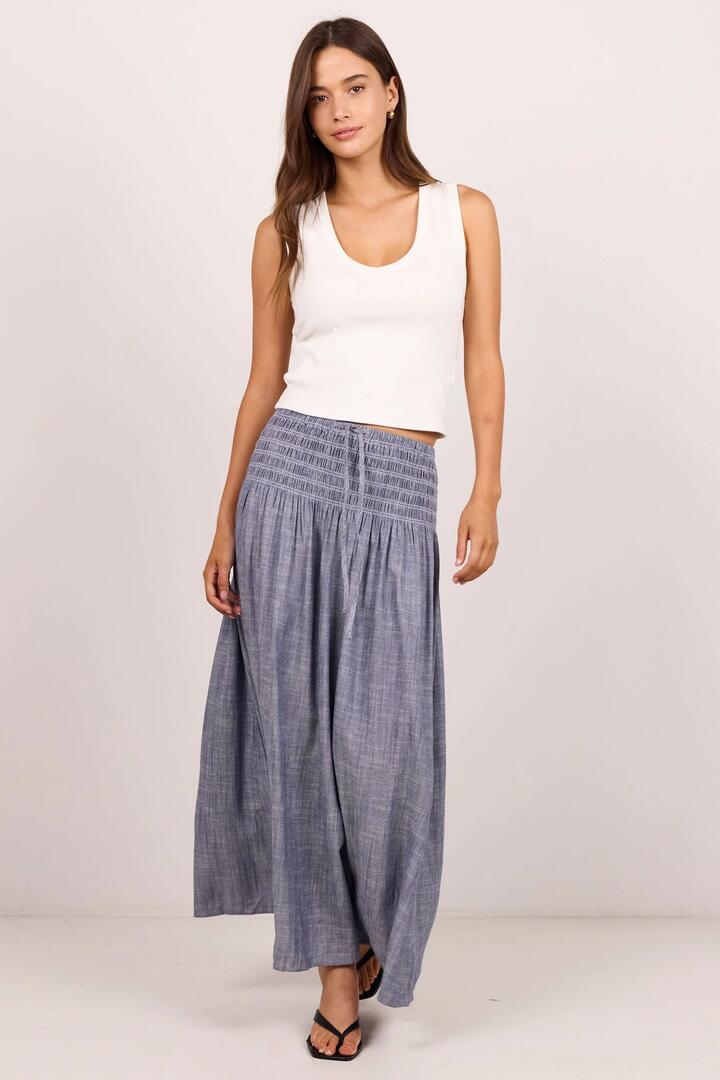 Image of a model wearing Skirts. Product name - Byron Light Blue Chambray Shirred Waist Maxi Skirt in Light Blue Chambray colour by brand - RE:UNION Label