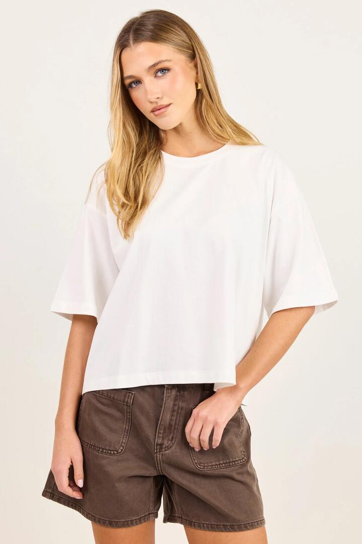 Image of a model wearing Tops. Product name - Cohesion White Oversized Boxy SS Tee in White colour by brand - Stories be Told