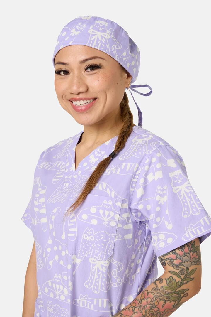 Image of a model wearing Uniforms & Workwear. Product name - Lilac Cat Scrub Hat in Lilac colour by brand - Gorman