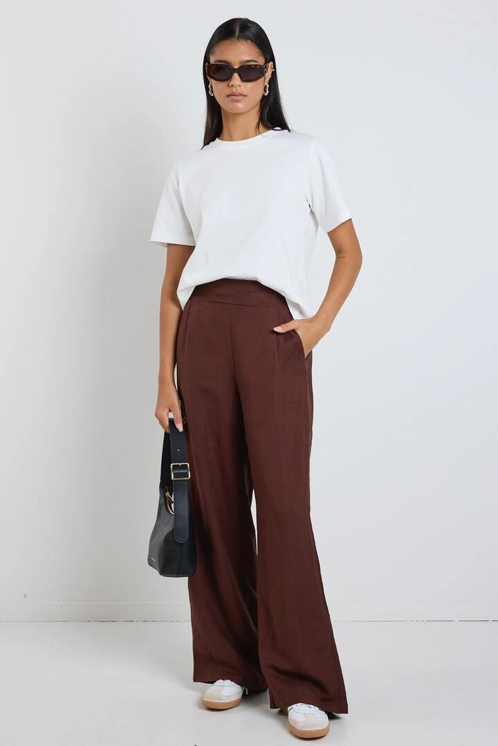 Image of a model wearing Pants. Product name - Guardian Chocolate Linen Viscose Elastic Back Pants in Chocolate colour by brand - Among the Brave