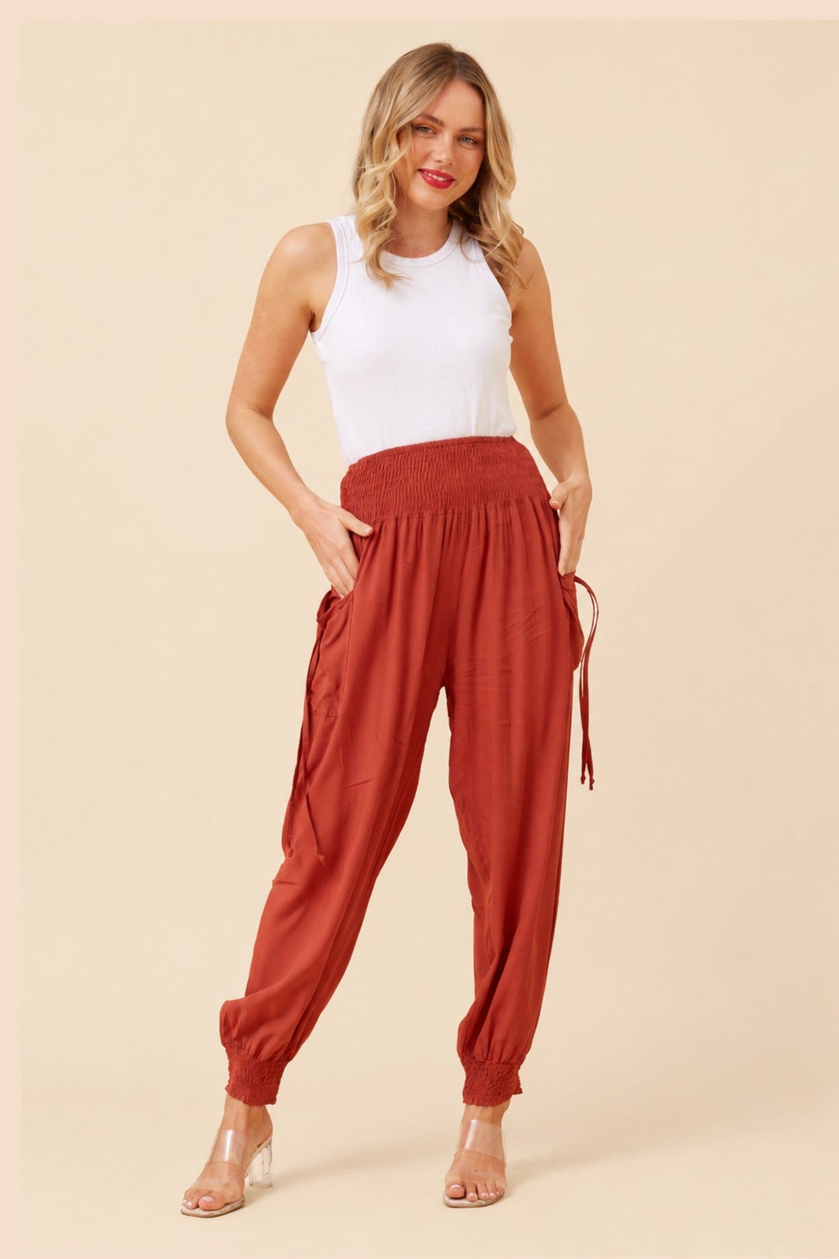 Image of a model wearing Pants. Product name - SOLID HAREM PANTS in Burnt Orange colour by brand - Caroline Morgan Australia