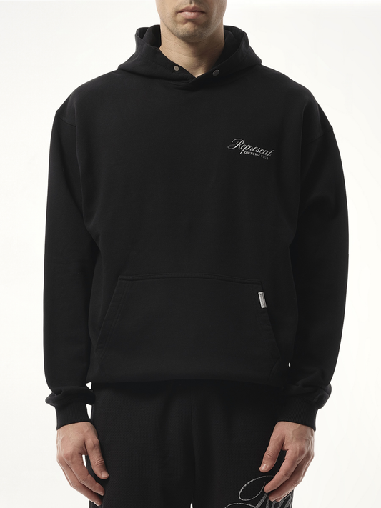 Image of a model wearing Outerwear. Product name - Represent Owners Club Script Hoodie in Black colour by brand - REPRESENT