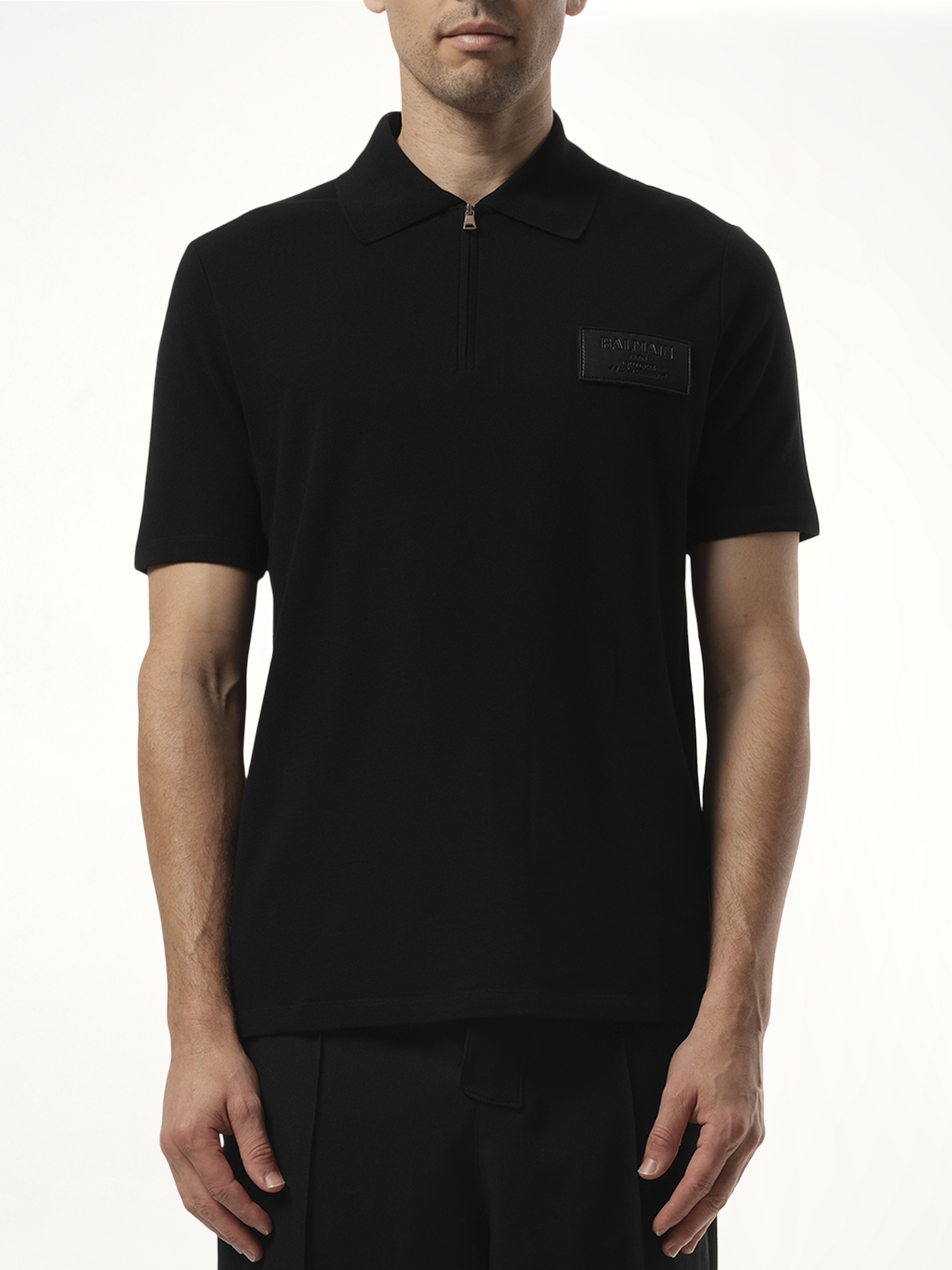 Image of a model wearing Tops. Productname: BALMAIN Small Leather Couture Label Zipped Polo in Black colour by brand - BALMAIN