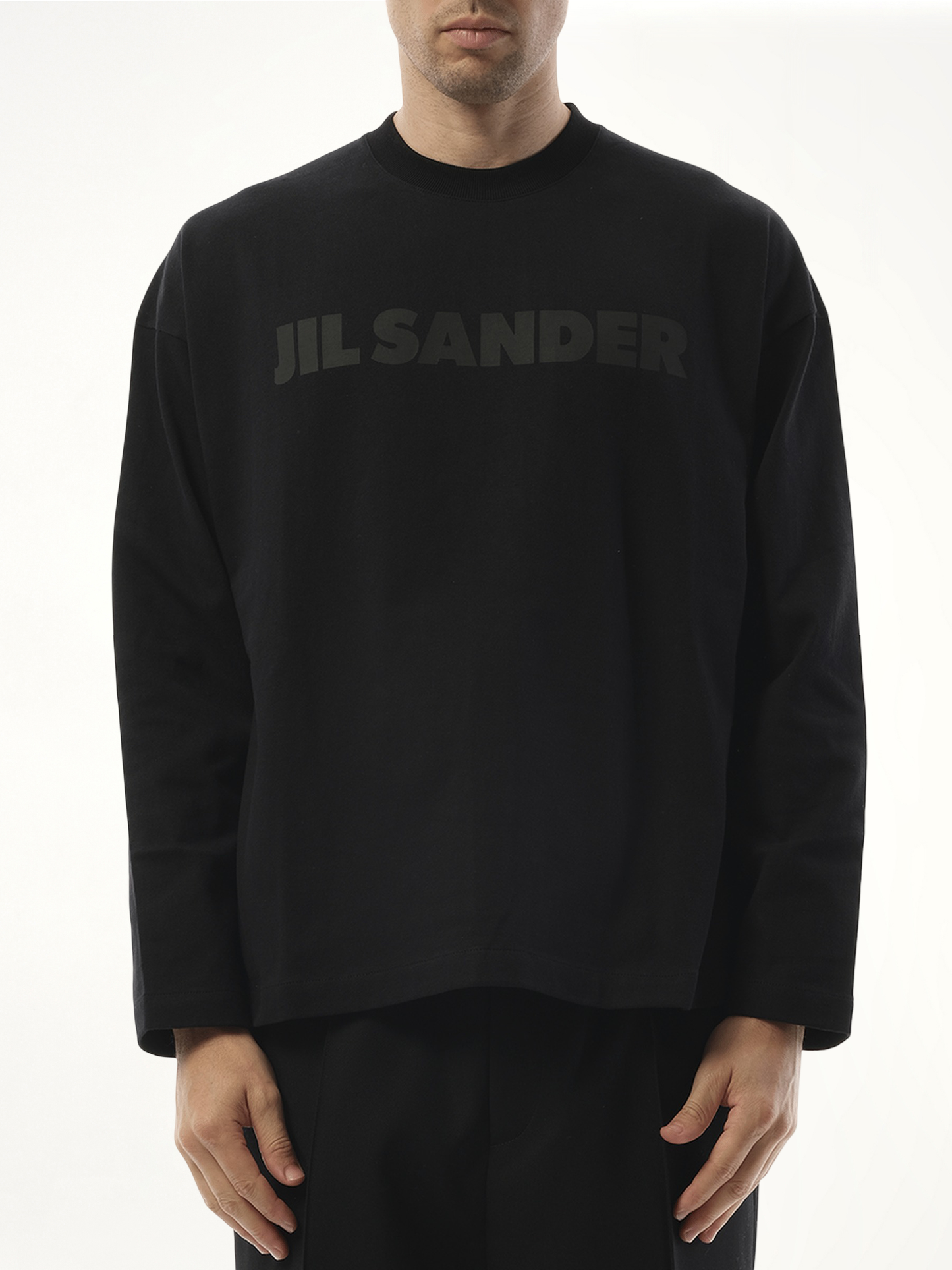 Image of a model wearing Tops. Product name - Tonal Jil Sander Logo Long Sleeve T-Shirt in Black colour by brand - JIL SANDER