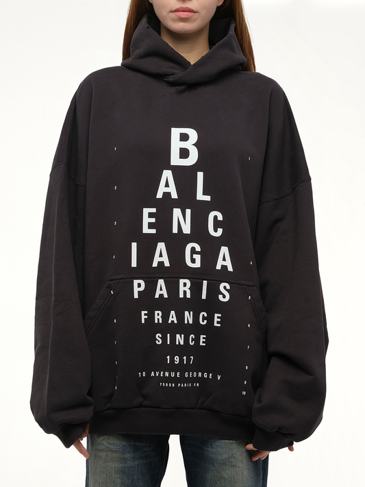 Image of a model wearing Outerwear. Productname: BALENCIAGA Eye-Test Large Fit Hoodie in Black colour by brand - BALENCIAGA