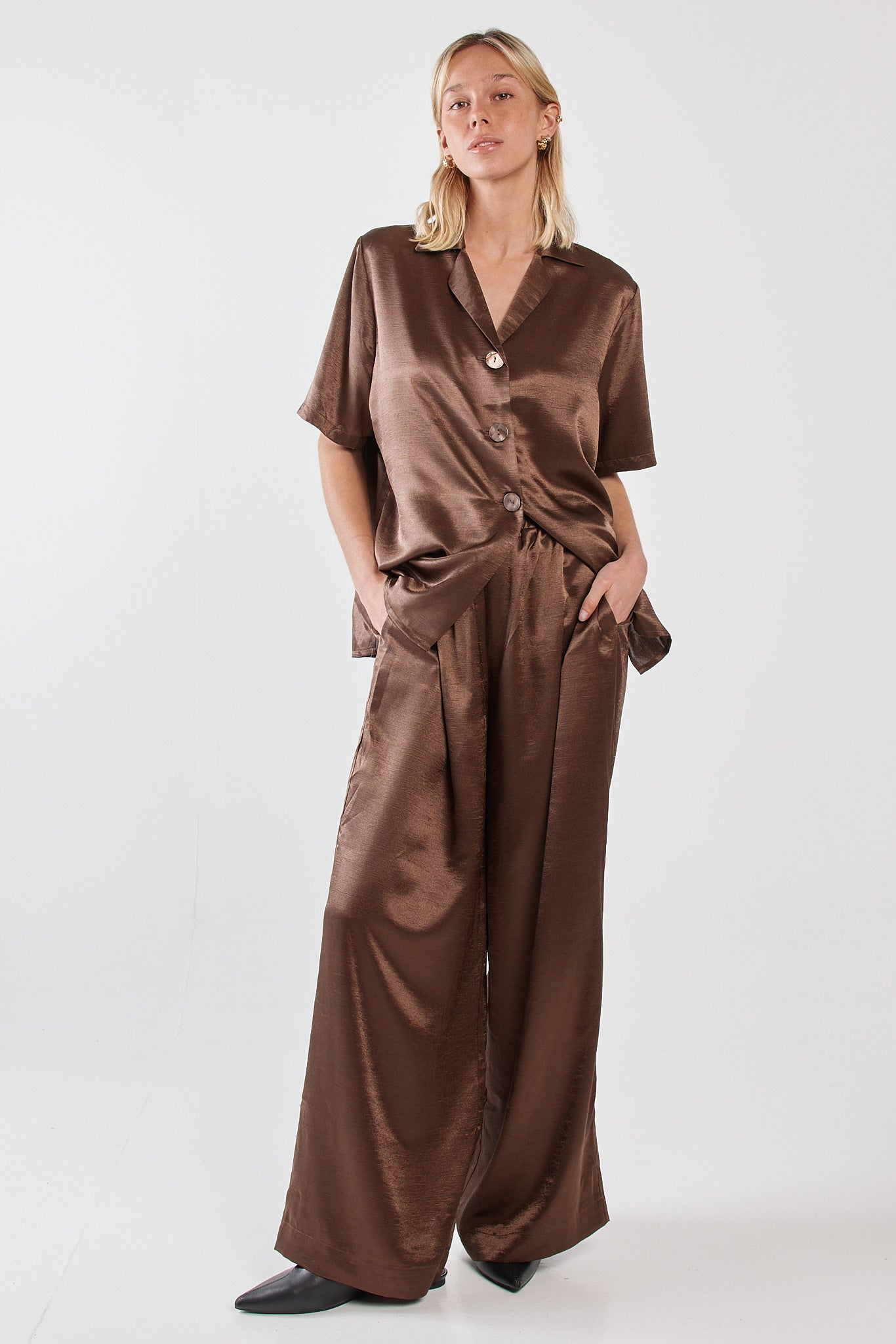 Image of a model wearing Pants. Product name - Eddy Crushed Satin Pant Chocolate in Chocolate colour by brand - Sass Clothing