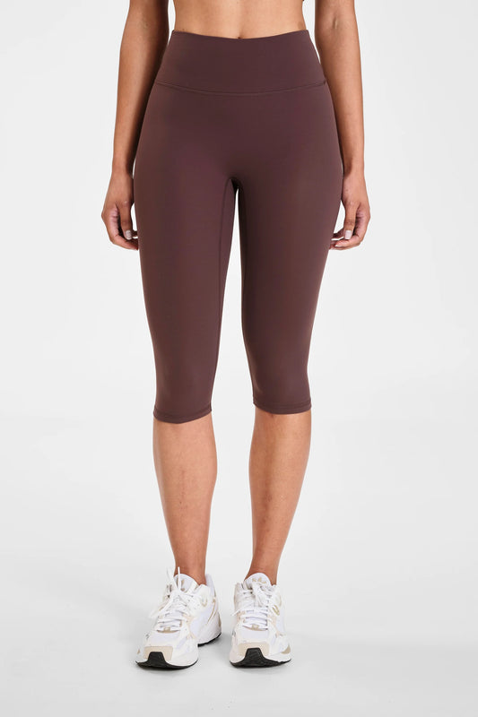Image of a model wearing Pants. Product name - ALLFENIX CloudCore Capri Legging in Espresso colour by brand - All Fenix