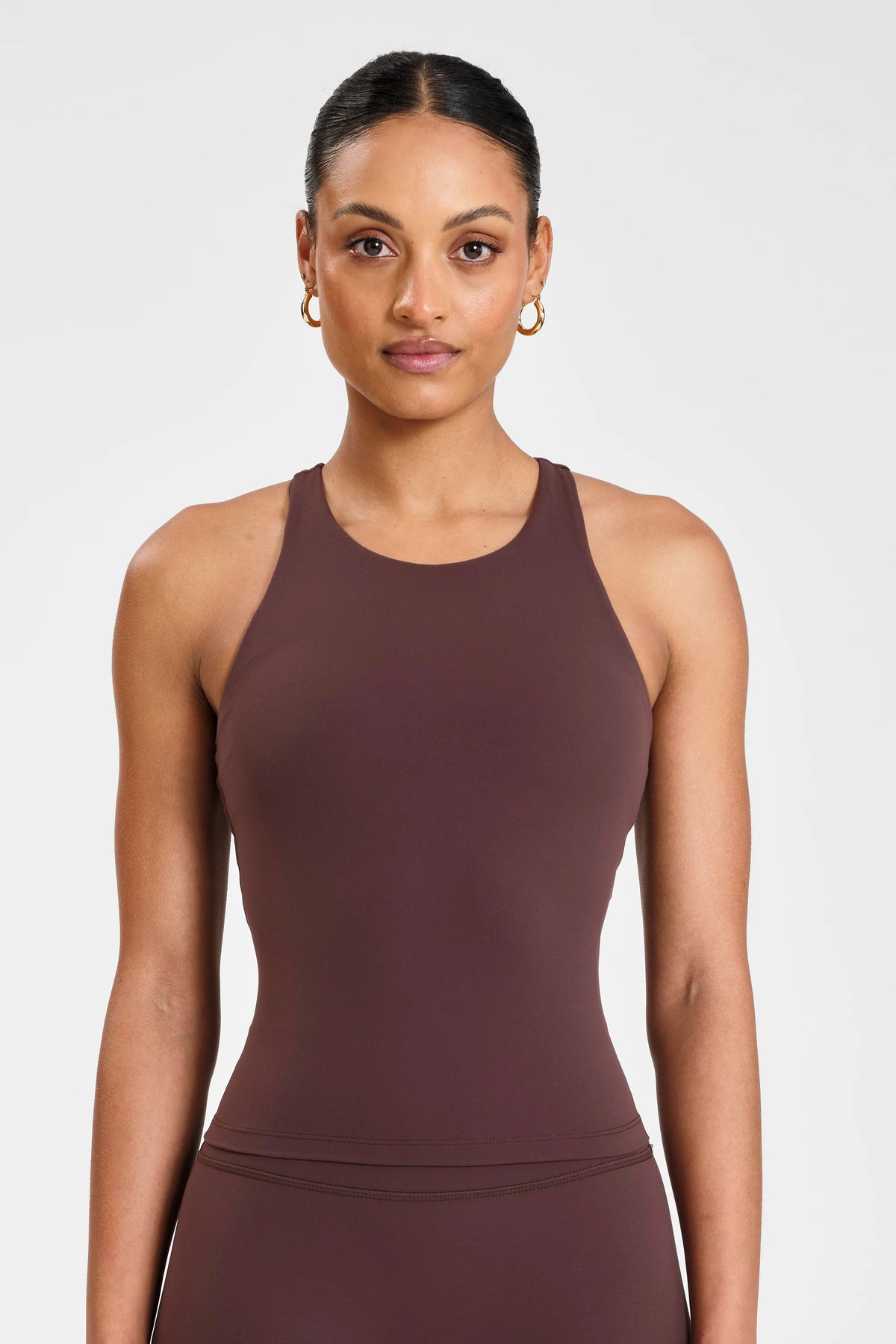 Image of a model wearing Tops. Product name - ALLFENIX CloudCore Racer Tank in Espresso colour by brand - All Fenix