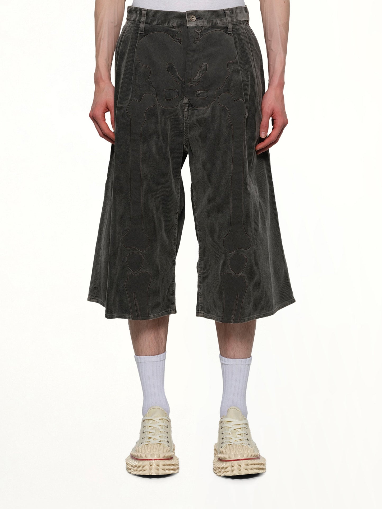 Image of a model wearing Shorts. Productname: DOUBLET Bone Applique Corduroy Croppedpants in GREY colour by brand - DOUBLET