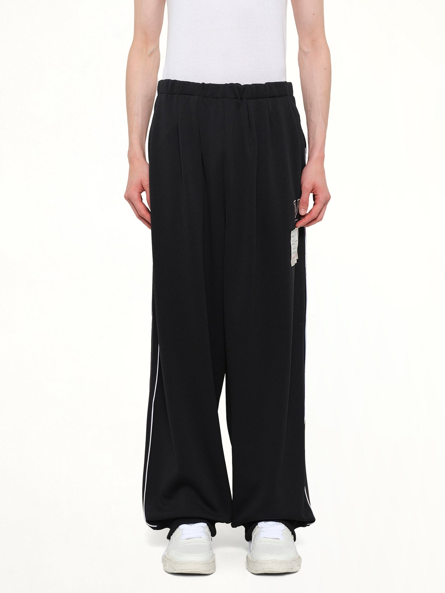 Image of a model wearing Pants. Product name - Amateur Sewn Track Pants in Black colour by brand - MAISON MIHARA YASUHIRO