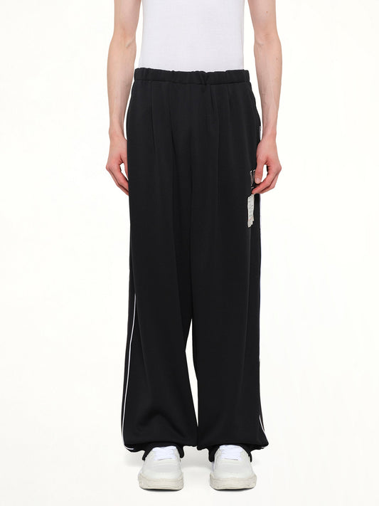 Image of a model wearing Pants. Product name - Amateur Sewn Track Pants in Black colour by brand - MAISON MIHARA YASUHIRO