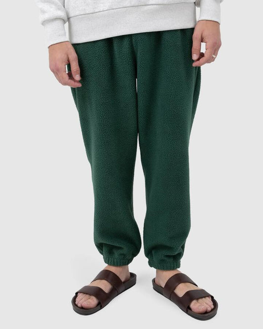 Image of a model wearing Outerwear. Productname: Rhythm Mens Reverse Fleece Track Pants Kelp - in Kelp colour by brand - Rhythm