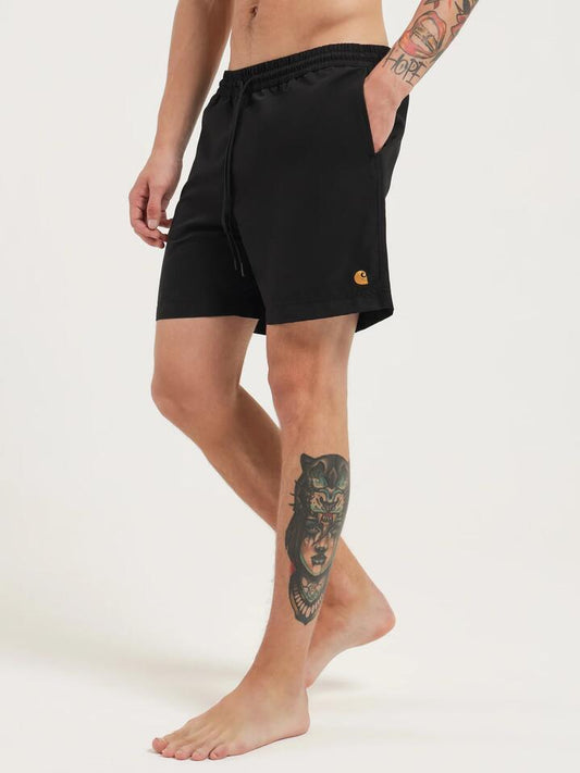 Image of a model wearing Shorts. Productname: Carhartt Wip Chase Swim Trunks in Black/Gold colour by brand - Carhartt Wip