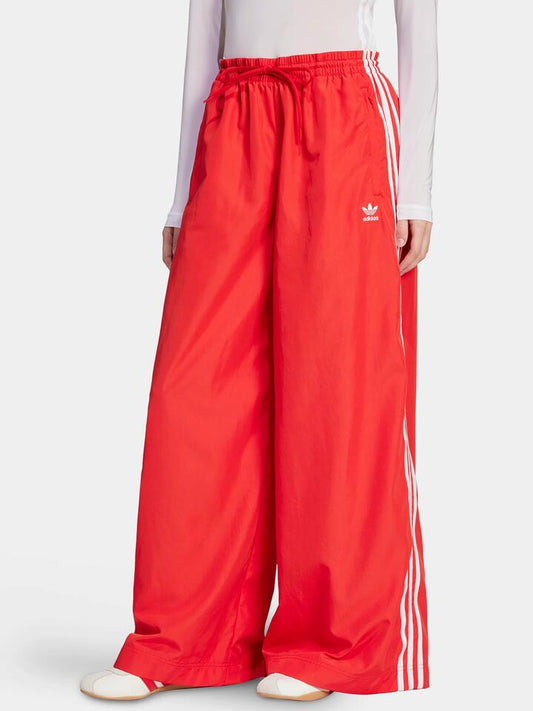 Image of a model wearing Pants. Productname: Adidas Oversized Track Pant in BETTER SCARLET colour by brand - Adidas