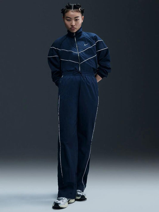 Image of a model wearing Pants. Productname: Nike Women's High-Waisted Woven Open-Hem Pants in ARMORY NAVY/WHITE colour by brand - Nike