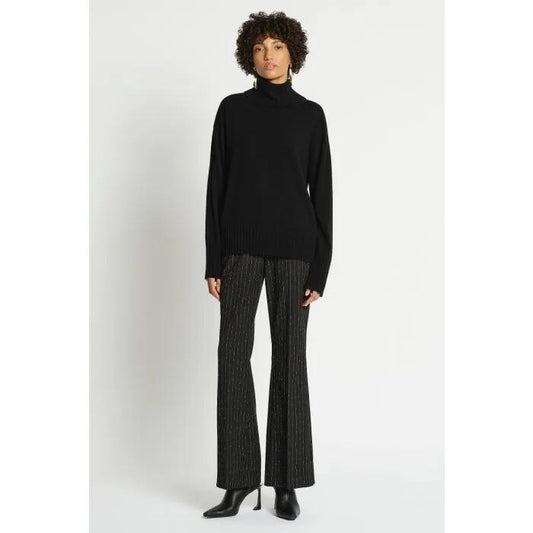 Image of a model wearing Outerwear. Productname: Lucillian Roll Neck Jumper in Black colour by brand - sass and bide