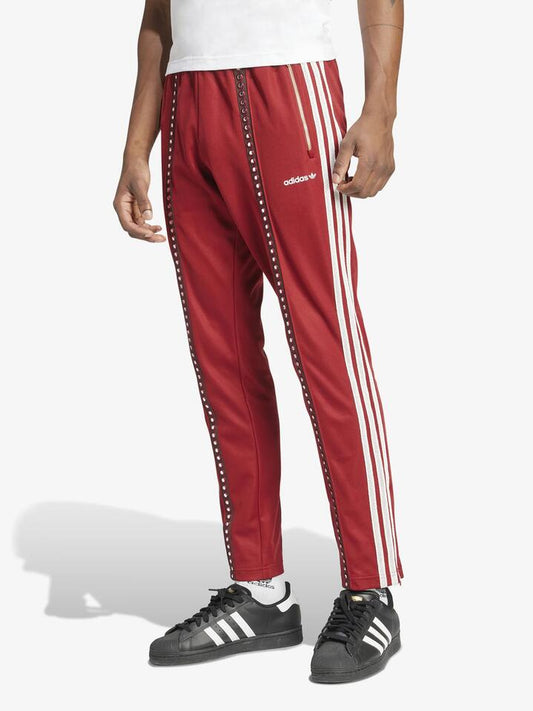 Image of a model wearing Pants. Productname: Adidas Track Pant in rust red colour by brand - Adidas