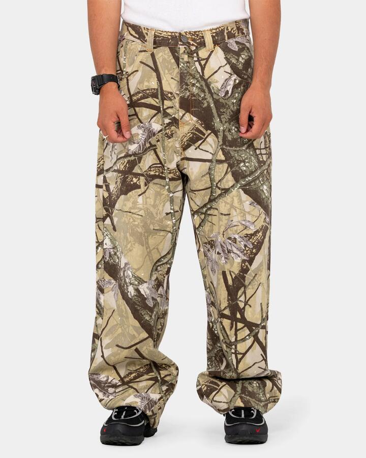 Image of a model wearing Pants. Product name - Rusty Mens Hoodus Rambo Baggy Pants Camo in Camo colour by brand - Rusty