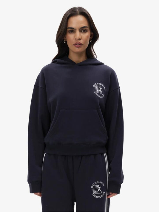 Image of a model wearing Outerwear. Productname: West Hollywood Sweat Club Running Hoodie in Navy colour by brand - West Hollywood Sweat Club