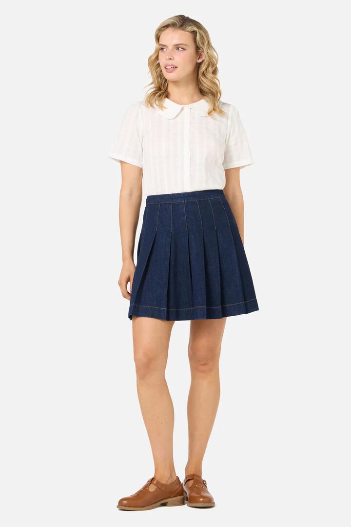 Image of a model wearing Skirts. Productname: Rae Pleated Denim Mini Skirt in Dark Denim colour by brand - Princess Highway
