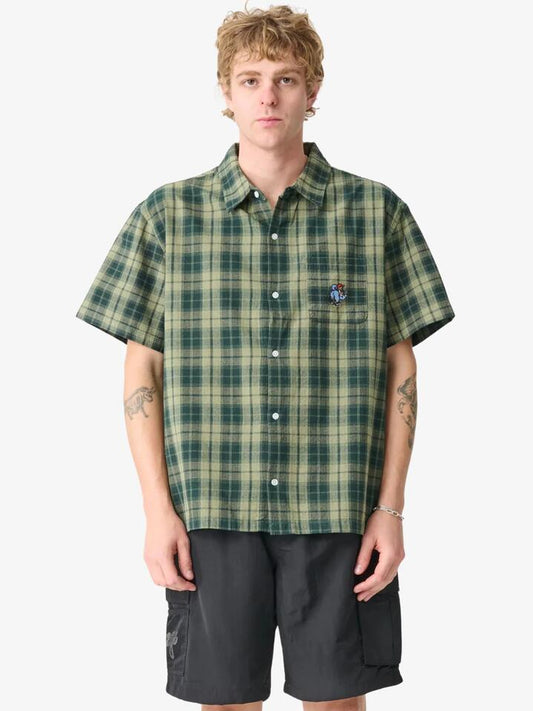 Image of a model wearing Shorts. Productname: Xlarge Artist Short Sleeve Shirt in Green colour by brand - Xlarge