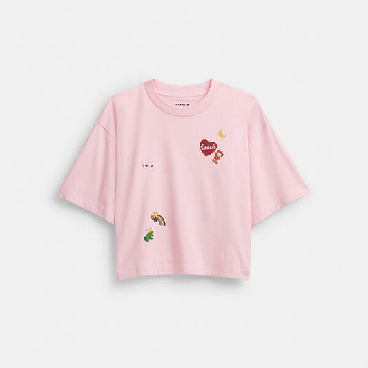 Image of a model wearing Tops. Productname: Cropped T-Shirt In Organic Cotton With Sticker Patches in LIGHT PINK colour by brand - Coach Outlet Australia