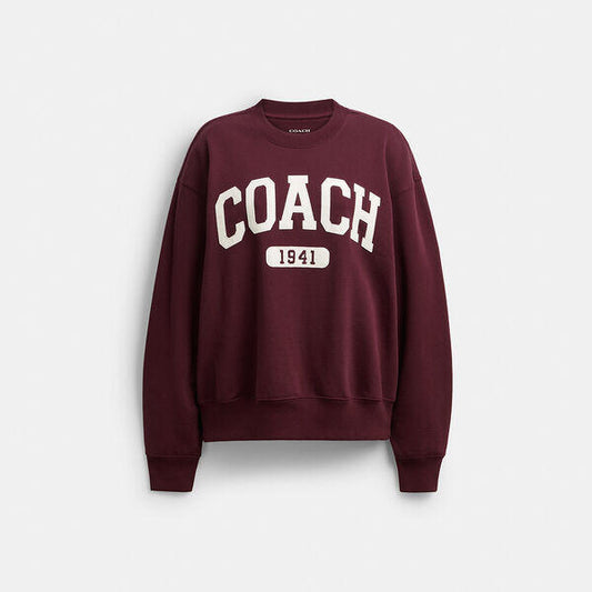 Image of a model wearing Outerwear. Productname: Sporty Signature Boyfriend Crewneck Sweatshirt in BURGUNDY colour by brand - Coach Outlet Australia
