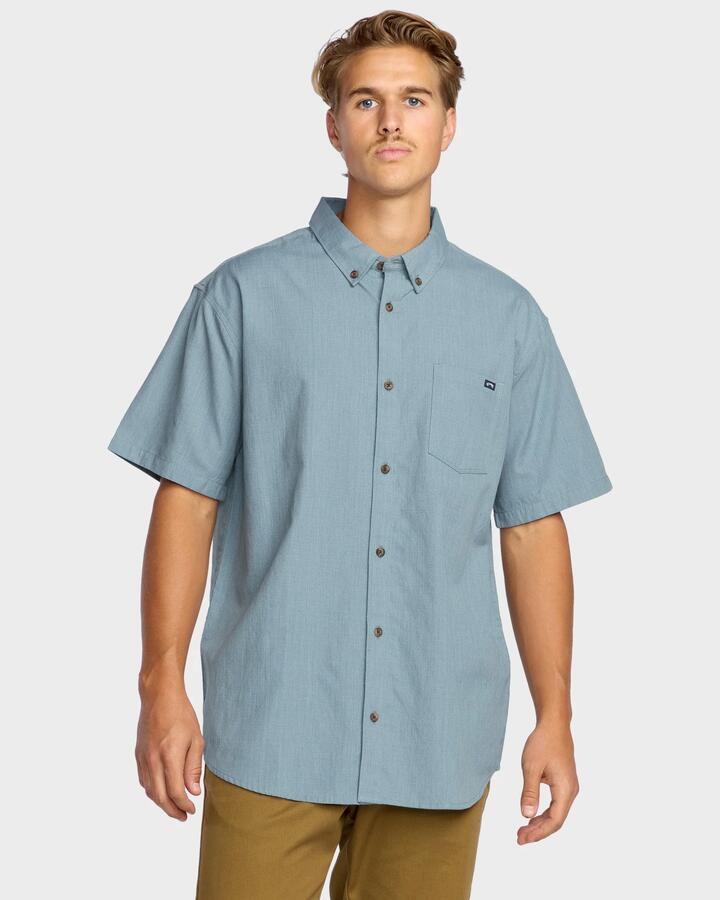 Image of a model wearing Tops. Product name - Billabong Mens All Day Short Sleeve Shirt Steel Blue in Steel Blue colour by brand - Billabong