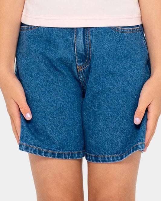 Image of a model wearing Shorts. Product name - Rusty Girls 8-14 Cyprus High Denim Shorts Mid Blue in Mid Blue colour by brand - Rusty