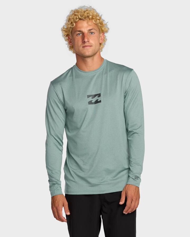 Image of a model wearing Tops. Product name - Billabong Mens All Day Wave Long Sleeve Rash Vest Sea Blue - in Sea Blue colour by brand - Billabong