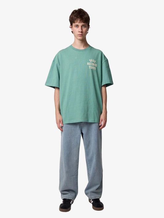 Image of a model wearing Tops. Productname: Deus Drive Far Away Tee in Malachite Green colour by brand - Deus