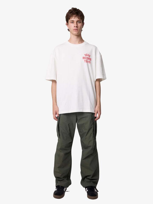 Image of a model wearing Tops. Productname: Deus Drive Far Away Tee in Vintage White colour by brand - Deus