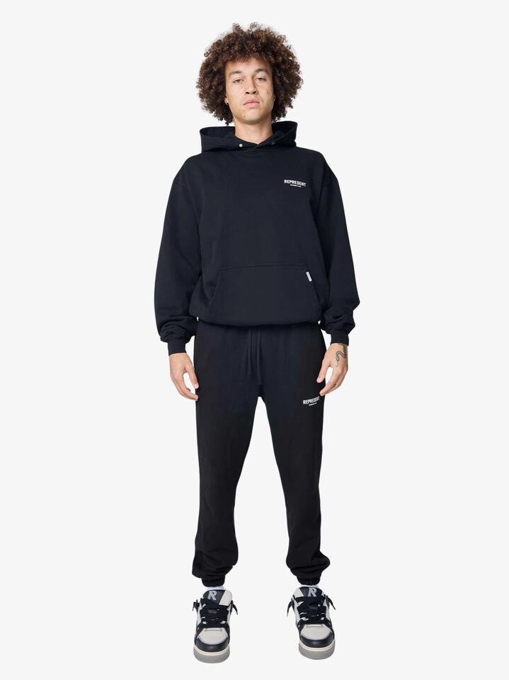 Image of a model wearing Pants. Productname: Represent Represent Owners Club Sweatpants in Aged Black colour by brand - Represent