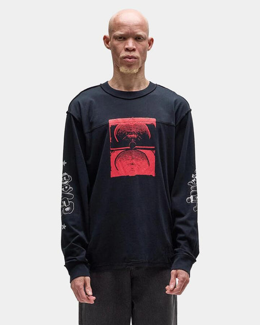Image of a model wearing Tops. Product name - Former Mens Immerse Long Sleeve T-Shirt Black in Black colour by brand - Former